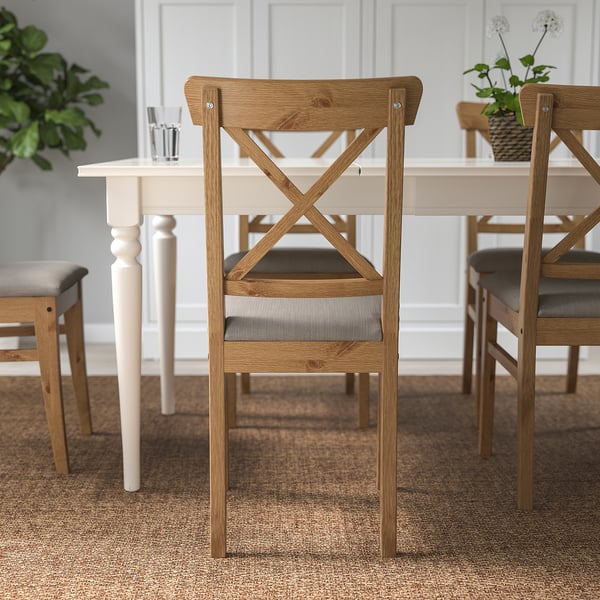 Wooden dining chair with padded seat set around a white table.