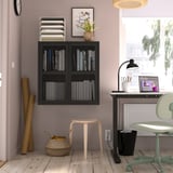 Black IVAR shelf with books on purple wall. Stool, basket. Desk with laptop, lamp, chair. Clock, art, window.