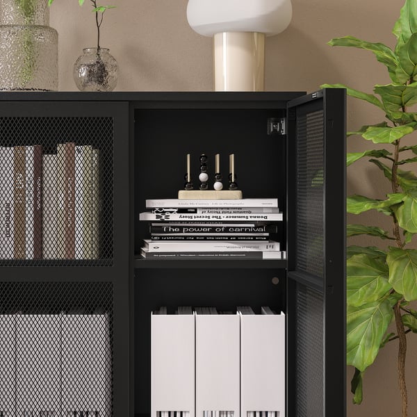 Black IVAR cabinet with shelves holding books and decor, anchored.