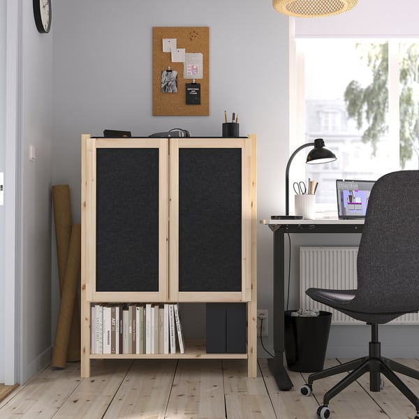 IVAR light wood cabinet in office with black felt doors, neat between storage & desk, storing books & items.