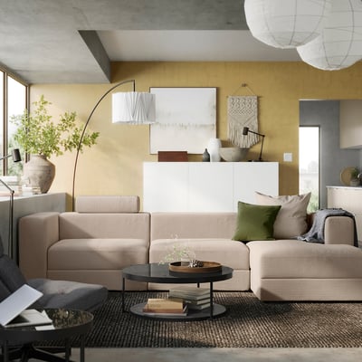 Modern living room with beige JÄTTEBO sofa, yellow wall, grey area rug, and hanging lights.