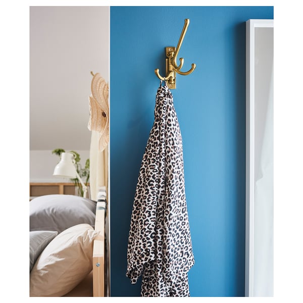 Bedroom with blue wall, scarf on gold hook, bed with pillows.