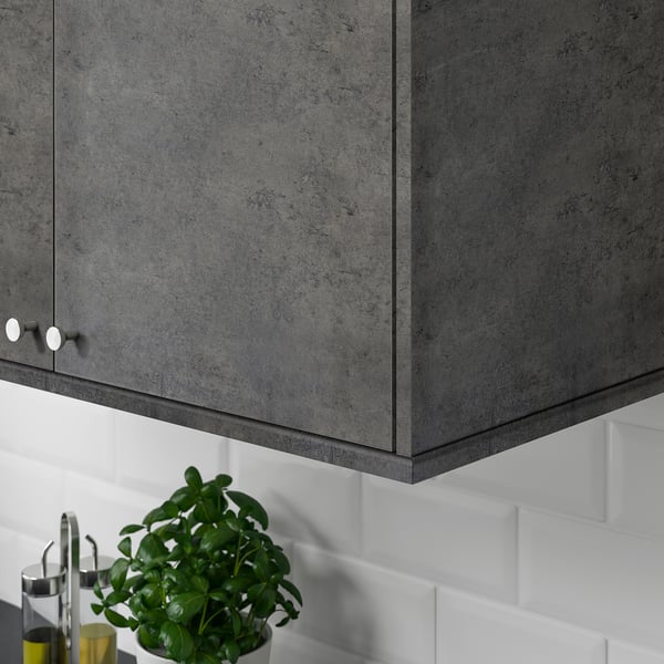 Dark gray cabinet over white tiles with a green plant below.
