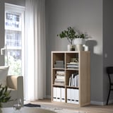 KALLAX shelves, light wood, near window, holding books & decor. Tall, simple, clean lines.