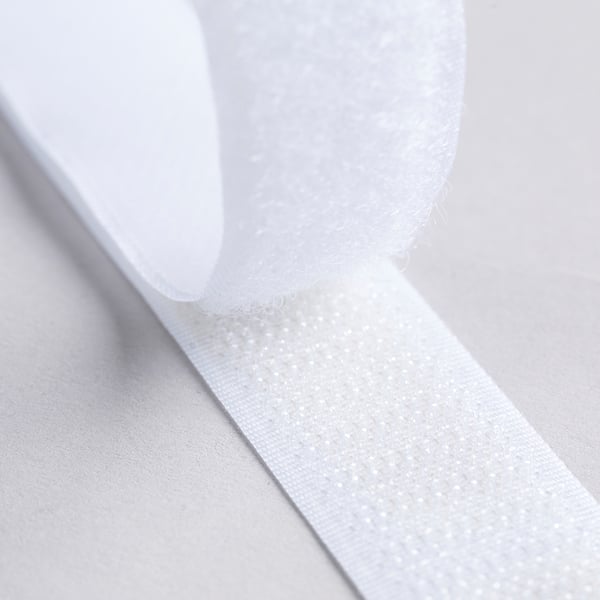 Close-up of white heat-bonding tape, showing texture and thickness. Ideal for no-sew fabric hemming.