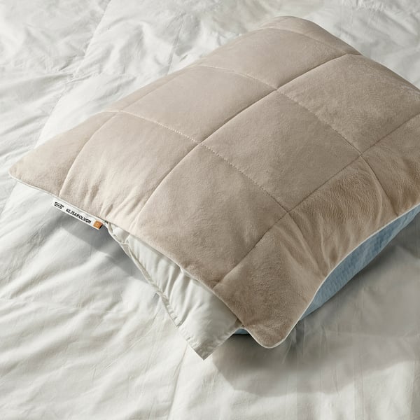 Pillow protector with cooling blue and warming beige sides on a bed, showcasing its dual comfort feature.
