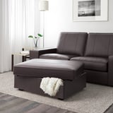 Dark leather living room set with ottoman, featuring storage underneath. White throw blanket resting on ottoman.
