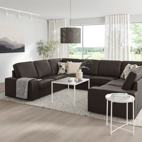 Modern living room with large grey KIVIK sofa, white tables, and nature view.
