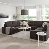 Modern living room with large grey KIVIK sofa, white tables, and nature view.