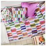 Brightly colored striped bedding with floral pillows.