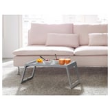 Modern bed tray on a couch with bowls, glasses, and fruit, ideal for meals and snacks.