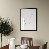 Minimalist dining room with art print, table, and decorative jug.