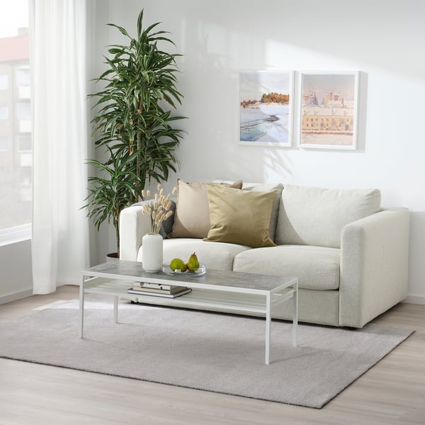 Modern living room with KNARDRUP rug, sofa, marble table, plant, and wall art. Recycled polyester rug.