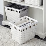 White woven baskets stored on shelves. Bottom basket holds magazines; top holds folded fabric.