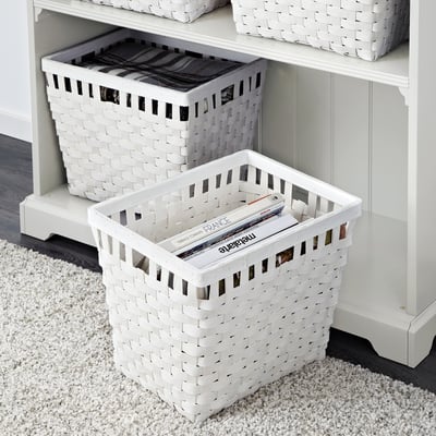 White woven baskets stored on shelves. Bottom basket holds magazines; top holds folded fabric.