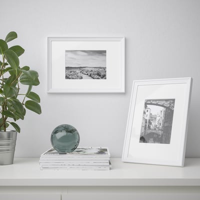 White shelf with glass orb, plant, & black/white art.