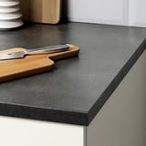 Modern kitchen countertop with dark surface, wooden cutting board, and knife. Easy-to-clean melamine finish.