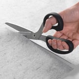 Hands holding scissors cutting a gray felt mat, creating a drawer liner with non-slip functions.