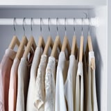 Wooden hangers with grooves for pants and shirts in closet.