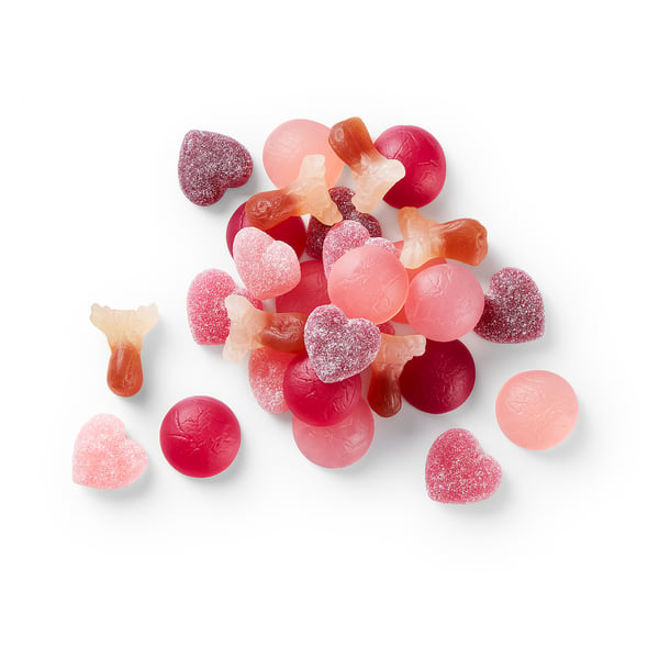 Assorted colourful gummies heap: hearts, circles, fish; red, pink, orange tones.