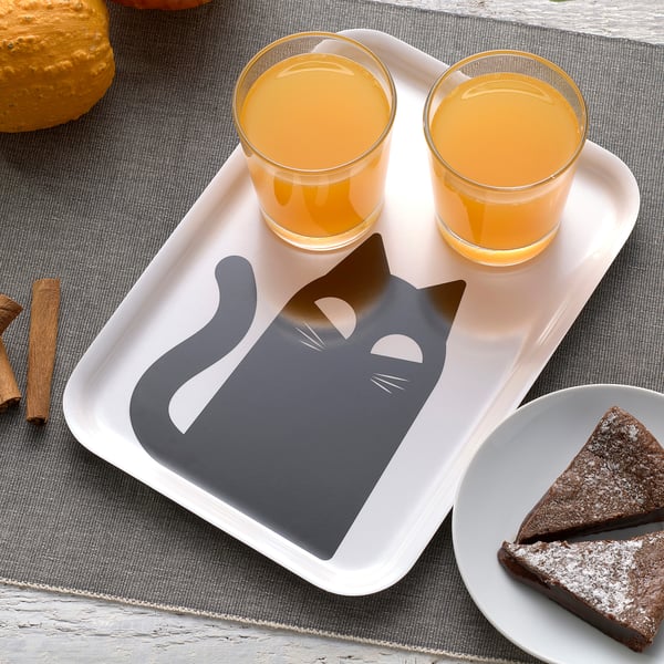 Tray with cat design holds two orange juices and cake slice.