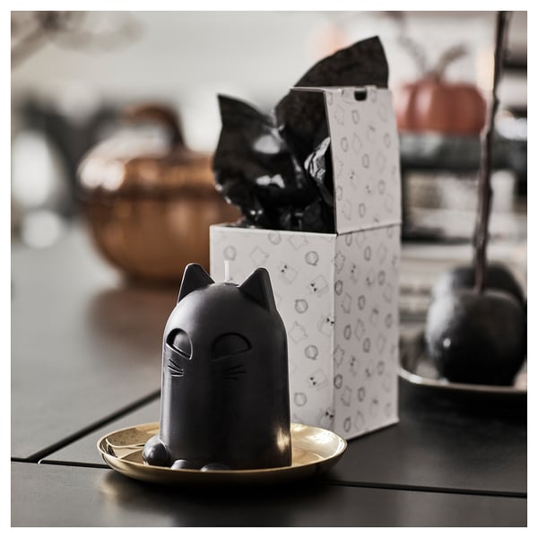 A cat-shaped candle sits on a plate, safely away from flammable items. Its unlit, with a trimmed wick ready to be lit.