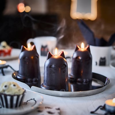 KUSTFYR black cat candles, lit, on tray, surrounded by decor.