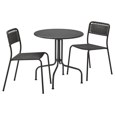 Black outdoor furniture set with round table and wicker chairs. Modern, stackable design.