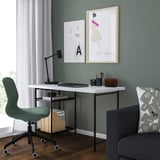 Home office setup: white LAGKAPTEN desk with black chair, grey couch, art prints, lamp, wooden floor.