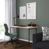 Modern home office with green LAGKAPTEN desk, matching green chair, black lamp, framed art, and gray couch with patterned pillow.
