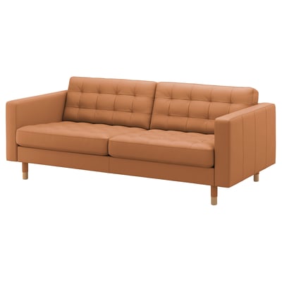 A modern, tan-colored, three-seater sofa named LANDSKRONA. It tufted leather upholstery, wooden legs, and a streamlined design for comfort and style.