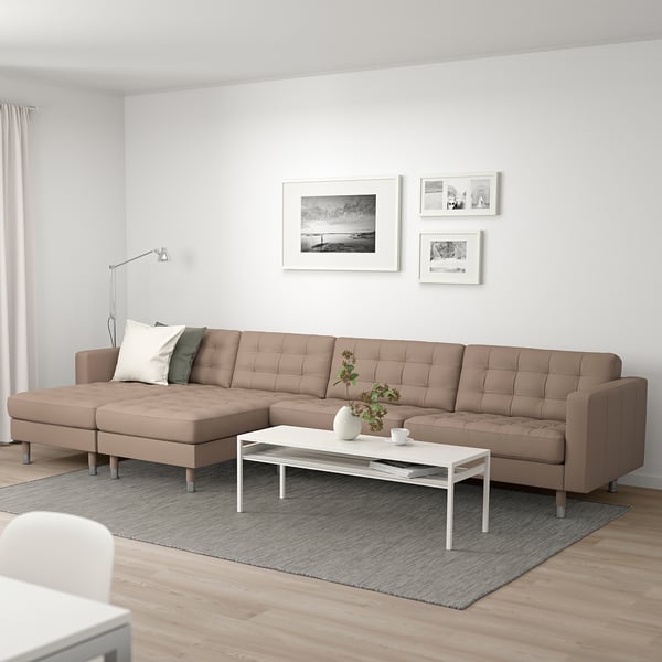 A modern living room with a large beige l-shaped leather sofa, a white coffee table, and framed pictures on the wall.