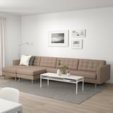 A modern living room with a large beige l-shaped leather sofa, a white coffee table, and framed pictures on the wall.