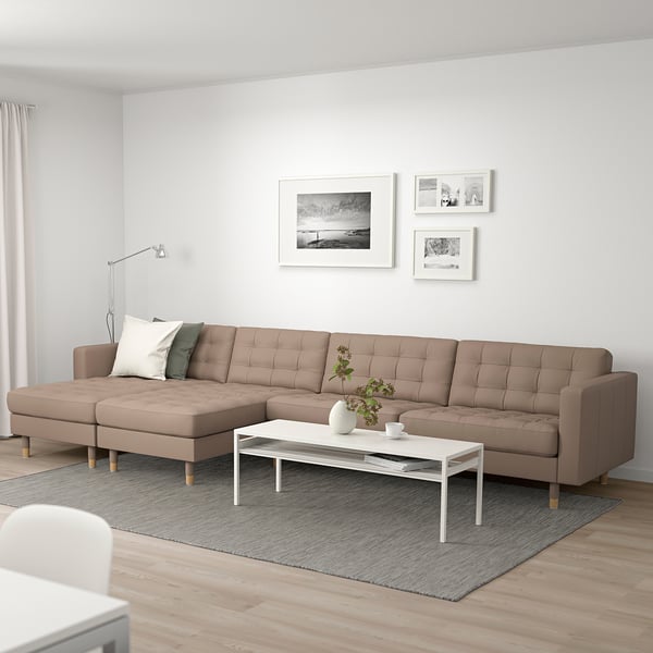 Modern living room with landkrona sectional sofa, rug, coffee table, art, and lamp.