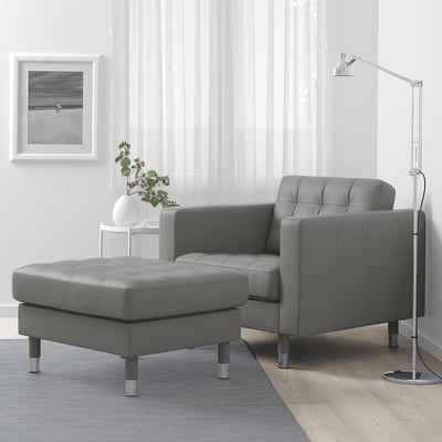 Modern living room with grey LANDSKRONA armchair, ottoman, and lamp. White walls with a framed photo.