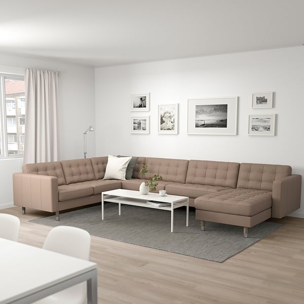 Modern living room with beige sofa, white coffee table, black-and-white photo gallery. Light wood floors and rug. Cozy ambiance.