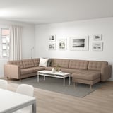 Contemporary living room with beige l-shaped sofa, black-and-white photos, white coffee table, gray rug, and bright decor.