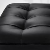 Black leather seat detail, showcasing smooth surface and stitching.