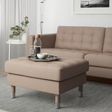 LANDSKRONA footstool in beige next to sofa in modern living room.