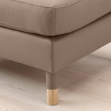 Close-up of a high-quality leather footstool with wood legs on a hardwood floor.