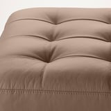 Modern footstool with ribbed, tan leather design, offering luxurious comfort.