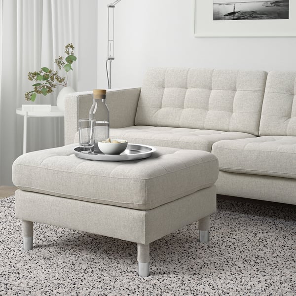 Modern light gray fabric LANDSKRONA footstool, chrome legs. It matches a large sofa, sits next to a vine plant. 10 year guarantee.