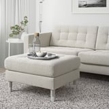 Modern light gray fabric LANDSKRONA footstool, chrome legs. It matches a large sofa, sits next to a vine plant. 10 year guarantee.