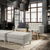 Modern living space with gray footstool, sofa, and lanterns.