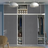 Modern wardrobe with grey felt sliding doors, hanging clothes, shelves, and storage baskets, lit by white pendant lamps.