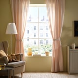 Cozy room with LENDA curtains, armchair, & side table.