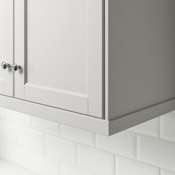White kitchen cabinet with chrome knobs, positioned above white tiled backsplash.