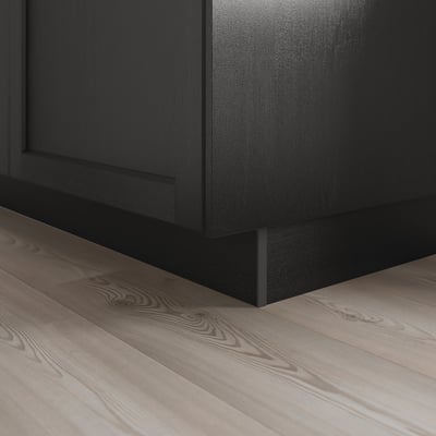 Black kitchen cabinet plinth covering floor gap, shown on wooden floor.