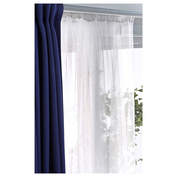 Window with sheer white LILL curtains beside solid navy blue curtains, diffusing daylight while offering privacy.
