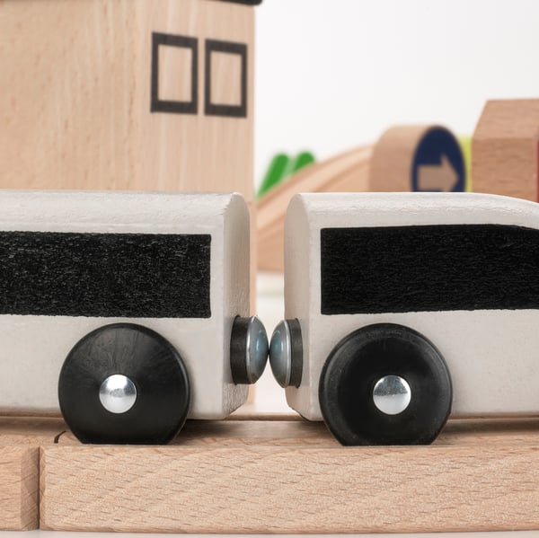 Minimalist wooden toy train cars on track. Black and white design, large wheels with metal axles. Crafted from high-quality beechwood, smooth finish.